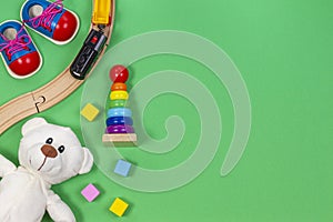 Baby kids toys background with toys train, colorful wooden blocks and plush teddy bear on light green background