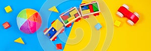 Baby kids toys background. White teddy bear, wooden train, toy car, colorful blocks on blue and yellow background
