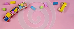 Baby kids toys frame with teddy bear, toy car, wooden train, colorful bricks on pink background. Top view