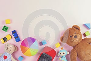 Baby kids toys frame with teddy bear, toy cars, colorful bricks on pink background