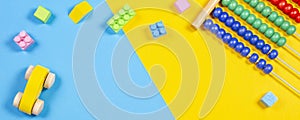 Baby kids toys frame with teddy bear, wooden toy train, car, colorful cubes on blue and yellow background