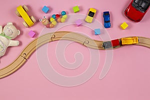 Baby kids toys frame with toy car, wooden train, colorful cubes, teddy bear, on pink background. Top view