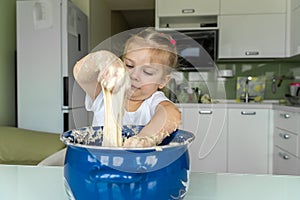 Baby kneads dough in a saucepan