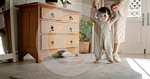 Baby, learning to walk and support from mother in bedroom of family home for development and balance. First steps, woman