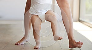 Baby, learning and walking with a child taking its first steps with his mother to learn to walk at home. Feet, legs and