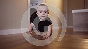 baby learns to crawl on the floor at home. happy family kindergarten kids concept. First steps, baby crawling front view