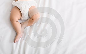 Baby legs and bottom in diaper on bed