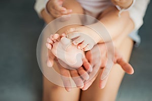 Baby legs in mother hands on white background