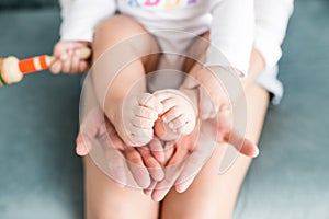 Baby legs in mother hands on white background