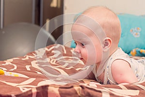 Baby lies on bed on his stomach