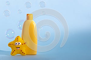 Baby liquid soap or washing gel with yellow star fish and flying soap bubbles. Children's hygiene. Copy space.