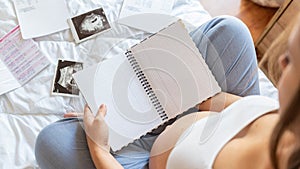 Baby list pregnant woman. Young pregnancy mother holding notepad. Pregnant lady writing check list of baby. Concept of