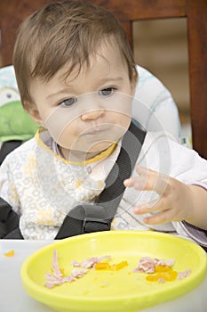 Baby looking away while sitting at table with plate