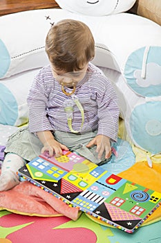 Baby looking down at colorful book with pictures