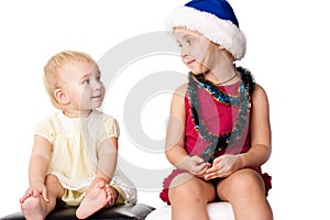 Baby looking at the sibling sister in Santa's hat