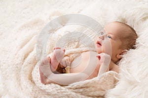 Baby looking up lying on Beige Blanket in Crib. Newborn Navel Treatment. One month Child Health Skin Care. Infant Development.