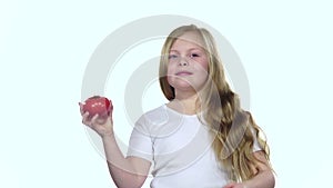 Baby looks at a tomato, admires it and shows a thumbs up. White background. Slow motion