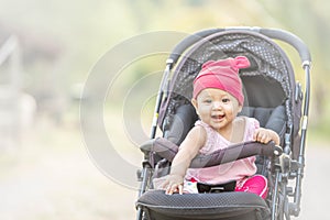 Baby lovely girl smiling and looking up to camera outdoors. Beautiful asian 6 months infant having happy time in th park