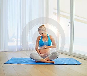 Baby loves it when she works out. a pregnant woman working out on an exercise mat at home.