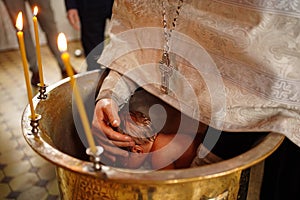 the baby is lowered into the font at the baptism in the church.