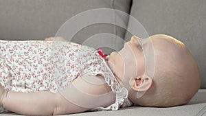 Baby lying on back on couch kicking arms and legs, energetic child, infancy