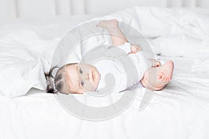 Baby lying on the bed at home with his feet up, the concept of a happy loving family and children