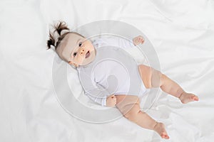 Baby lying on the bed at home on a white bed, the concept of a happy loving family and children