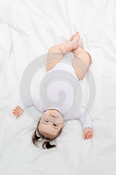 Baby lying on the bed at home on a white bed, the concept of a happy loving family and children