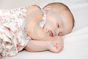 Baby lying on a bed while sleeping in a bright room