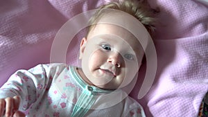 The baby is lying on the bed and smiling. Face close up.