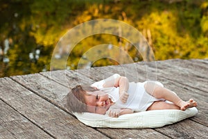 Baby lying on the blanket on pier hext to the river