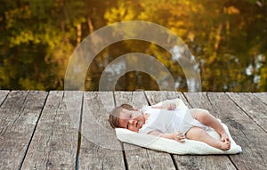 Baby lying on the blanket on pier hext to the river