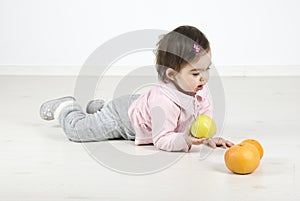 Baby lying on floor with fruits