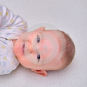 Baby is lying on the floor and smiling. Happy four-month-old child on the carpet