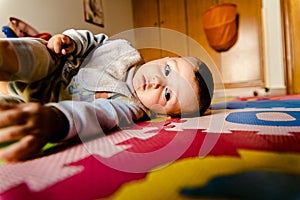 Baby lying on the floor watching the camera with curiosity