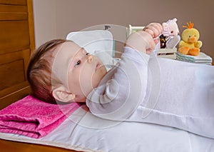 Baby lying playing with a children comb