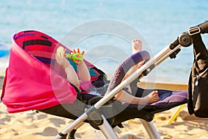 Baby lying in stroller on the beach