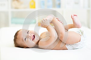 Baby lying on white bed and holding legs