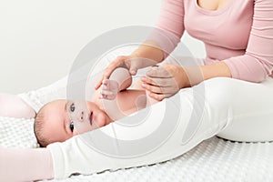 Baby massage background. Mother gently massaging her baby boy. Baby lying on back and looking at camera during massage.