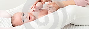 Baby massage banner. Mother gently massaging her baby boy while applying body lotion to his skin.