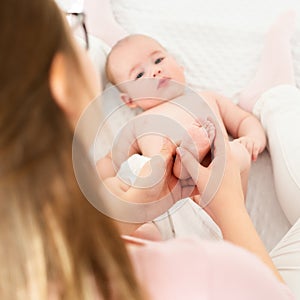Baby massage. Female therapist gently massaging babys foot. Mother touching her newborns bare feet, bonding time.