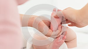 Baby massage. Female therapist gently massaging babys foot. Mother touching her newborns bare feet, bonding time. photo