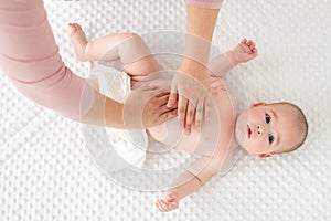 Baby massage. Female therapist gently massaging newborn baby boy. Mother applying body lotion to her infant baby boy.