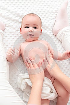 Baby massage. Female therapist gently massaging newborn baby boy. Mother applying body lotion to her infant baby boy. photo