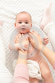 Baby massage. Female therapist gently massaging newborn baby boy. Mother applying body lotion to her infant baby boy. photo