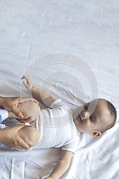 Baby massage. Mom doing gymnastics with kid. Mommy massaging cute baby boy. Moving baby`s legs to help relieve constipation