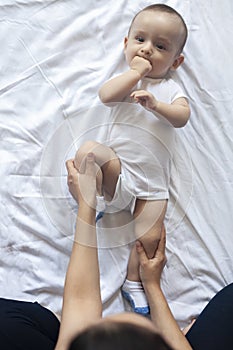 Baby massage. Mom doing gymnastics with kid. Mommy massaging cute baby boy. Moving baby`s legs to help relieve constipation. Youn