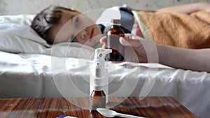 Baby medicine with sick child boy lying in sofa with a fever background, resting at home mom gives medicine to her son