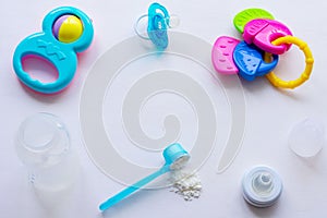 Baby milk powder, baby bottle and children`s toys on a light background flat lay
