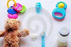 Baby milk powder, baby bottle and children`s toys on a light background flat lay